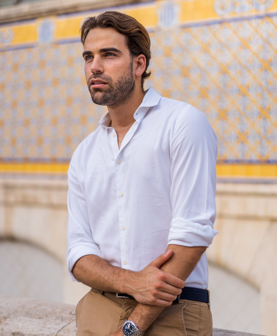 Man with full head of hair leaning against yellow wall - FUT Hair transplant NYC