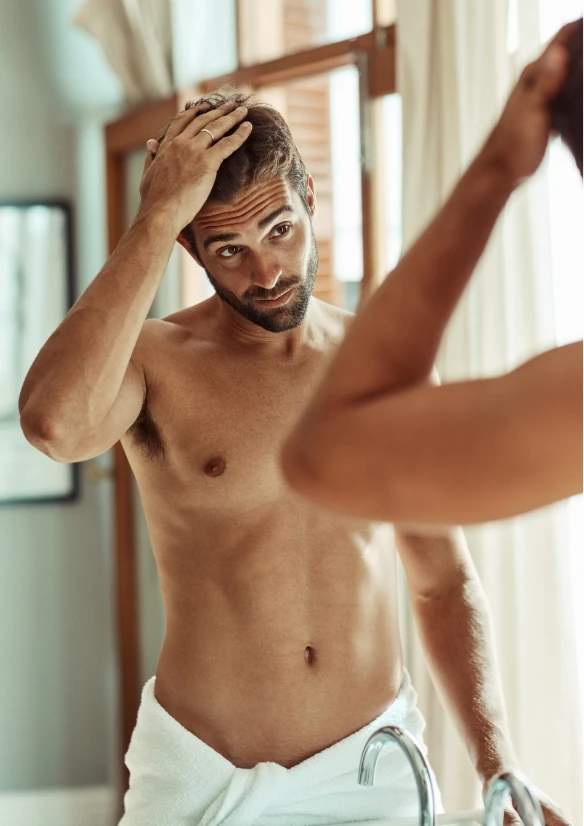 Male model examining hair line in bath room - Hair Treatment in NYC