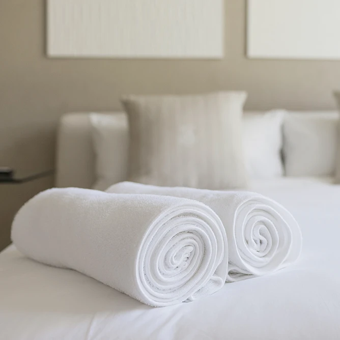 Image of towels rolled up on a hotel bed